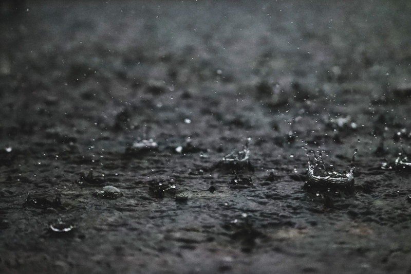 Gros plan de gouttes de pluie frappant un pavé, créant des ondulations et des éclaboussures.