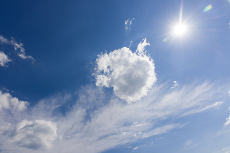 Ciel bleu frais avec une lumière du soleil brillante et des nuages blancs épars par une journée claire.