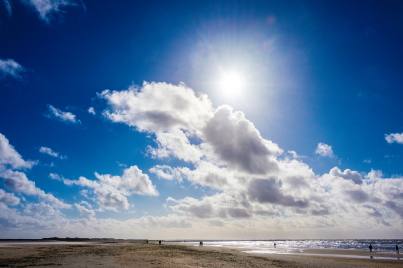 Bright sun shines through clouds over a beach