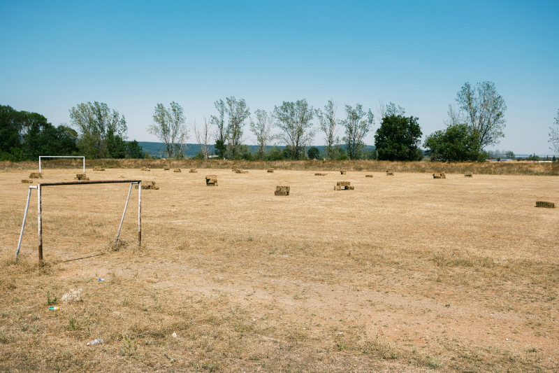 Terrain de football abandonné avec des balles de foin à Varna, en Bulgarie, sous un ciel bleu clair.