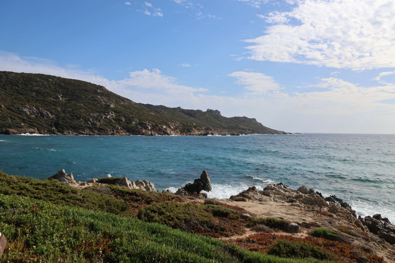 Littoral pittoresque avec des rochers escarpés et une mer turquoise sous un ciel d'un bleu éclatant.