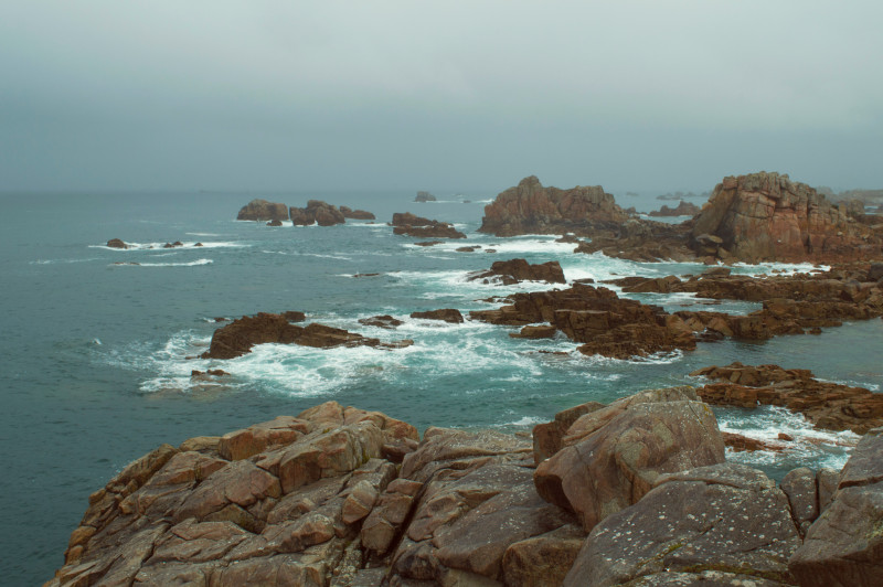 a view of a rocky coast with waves crashing on the rocks