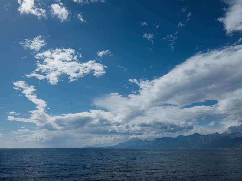 Vaste paysage marin dévoilant un horizon tranquille sous un ciel dramatique chargé de nuages.