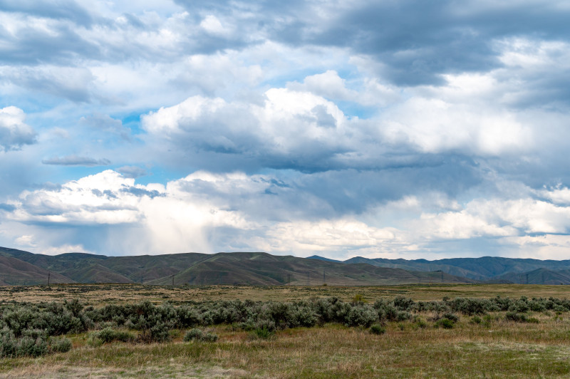 Vue panoramique d'un paysage montagneux serein sous un ciel vibrant et nuageux, parfait pour les thèmes de la nature et des voyages.