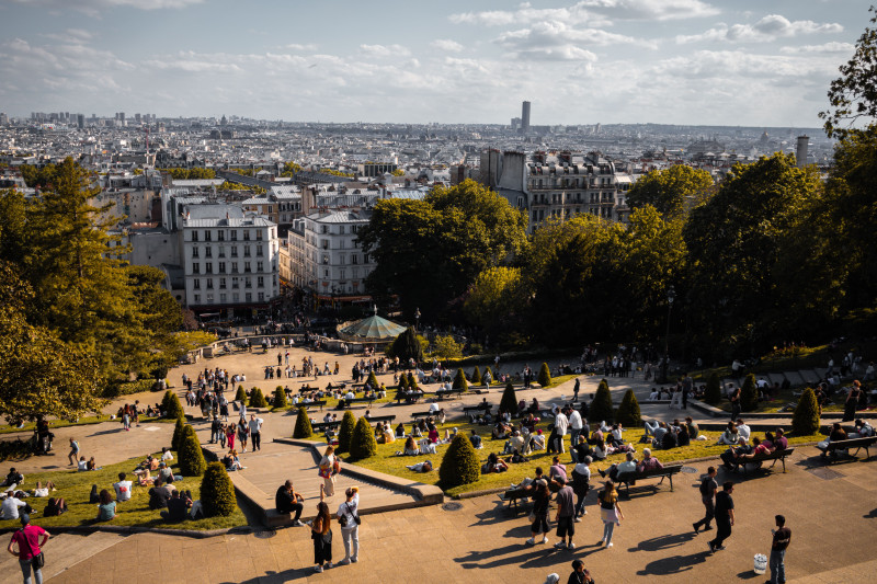 Une scène animée de personnes profitant d'une journée ensoleillée à Montmartre avec une vue panoramique sur Paris.