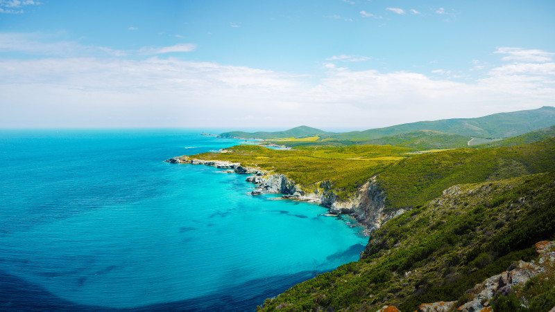 Vue aérienne à couper le souffle de la côte émeraude de Cap Corse, France, sous un ciel bleu clair.
