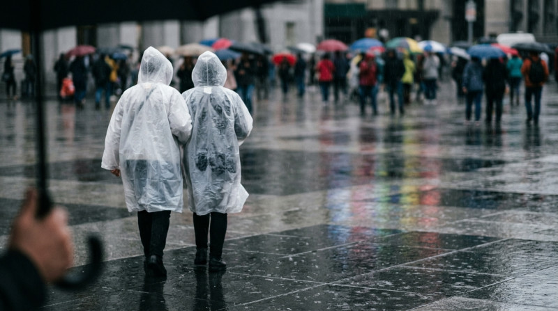 Deux personnes en ponchos blancs marchant sous la pluie dans une place urbaine avec foule et parapluies
