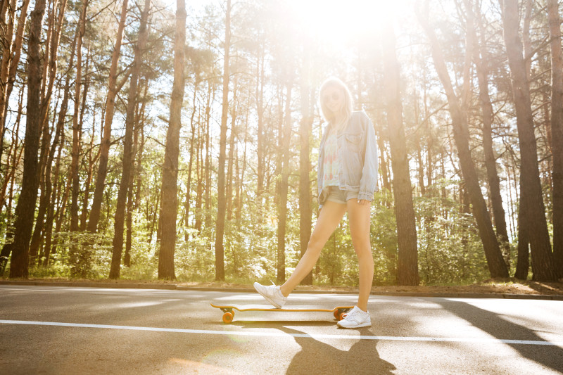 Jeune jolie femme sur planche à roulettes à l'extérieur