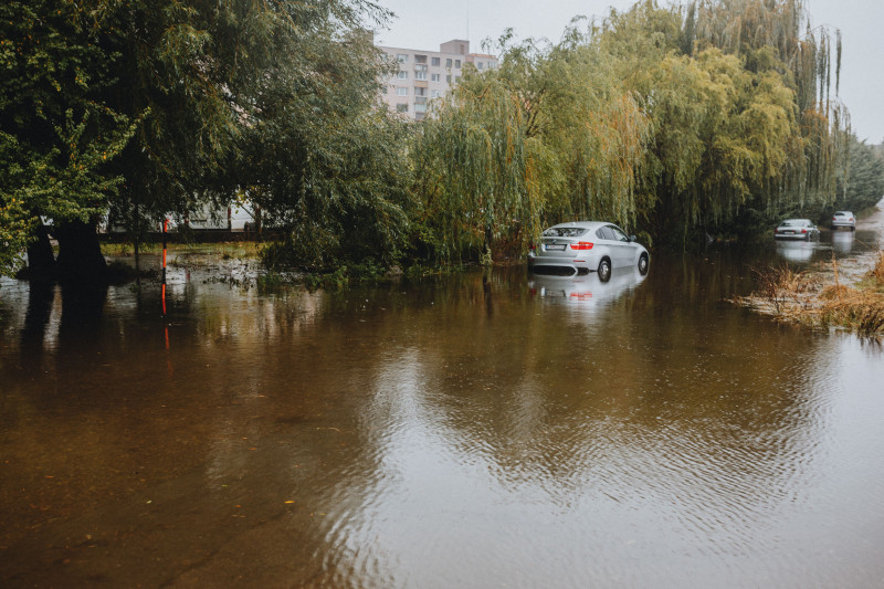 Voitures laissées à l'abandon sur une rue inondée entourée de grands arbres. Conséquences de la saison des pluies.