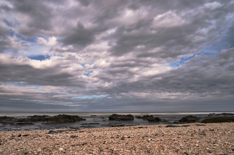Rocky shore with dramatic clouds over the ocean