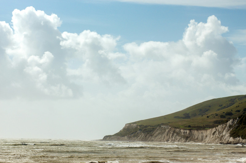 Coastal cliff with choppy ocean waves under cloudy sky