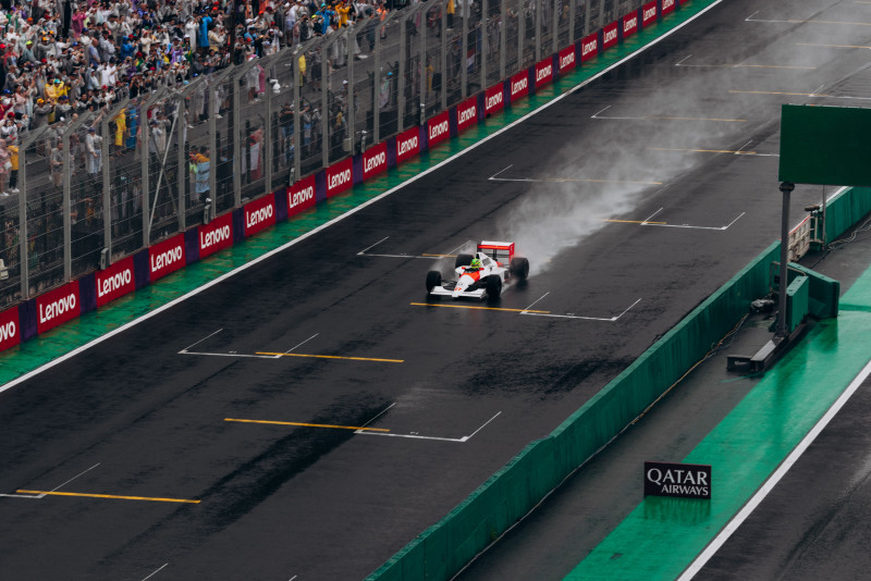 Une voiture de Formule 1 file sous la pluie à Interlagos, avec une foule en délire.