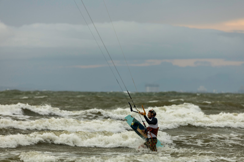 Action de kitesurf palpitante dans des vagues turbulence sous un ciel nuageux, capturant l'essence de l'aventure.