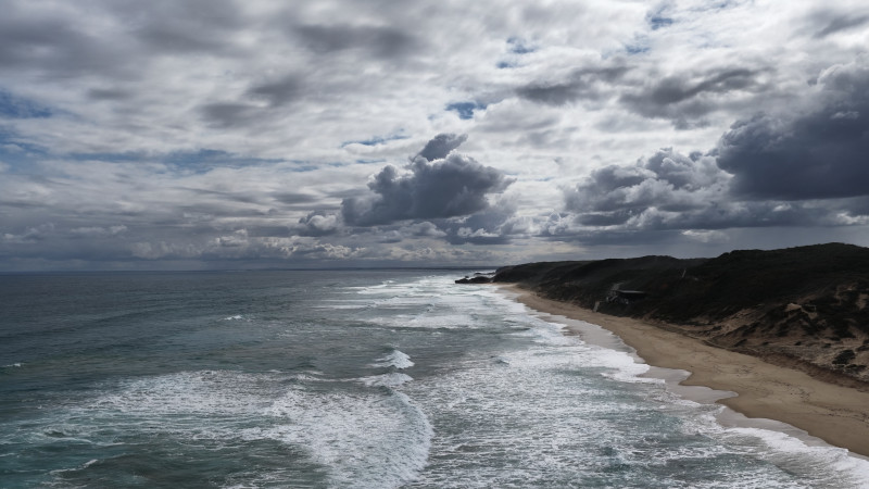 Vue aérienne de vagues spectaculaires déferlant sur la plage de Portsea sous un ciel nuageux