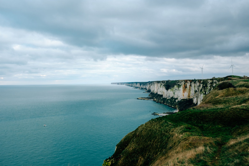 De magnifiques falaises accidentées à côté d'un vaste océan sous un ciel nuageux, capturant la majesté de la nature.