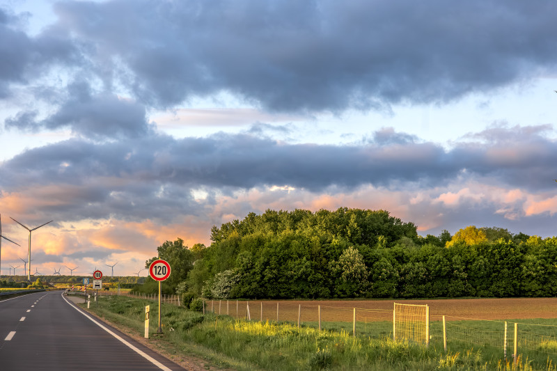 Limite de vitesse 120 signes forêt au bord de la route énergie éolienne en distance