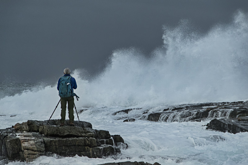 photographe sur les rochers en mer orageuse