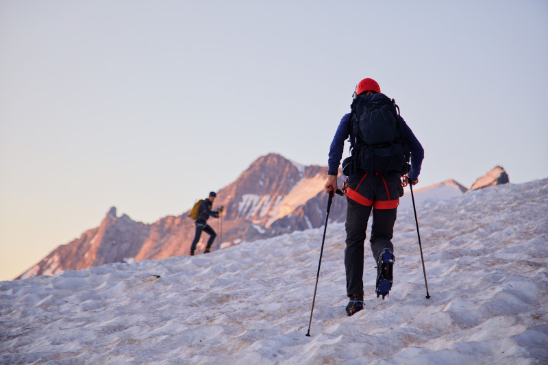 Des randonneurs gravissent des terrains enneigés en Provence-Alpes-Côte d'Azur au lever du soleil.