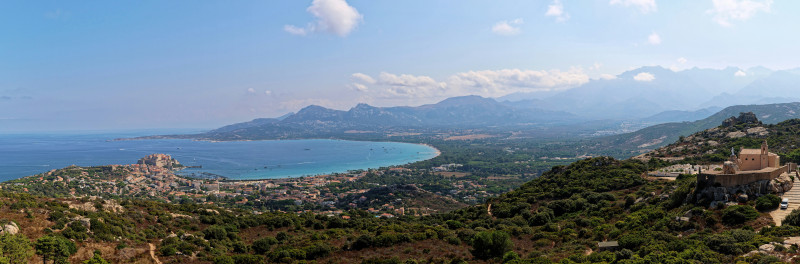 Panoramic view of a coastal town, bay, and mountains