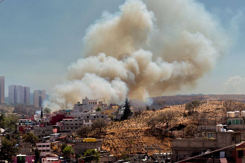 Paysage urbain montrant de la fumée d'un incendie derrière des bâtiments résidentiels avec la ligne d'horizon de la ville.