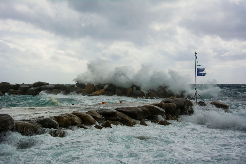 Des vagues puissantes s'écrasent contre la côte rocheuse sous un ciel nuageux, créant une scène marine intense.