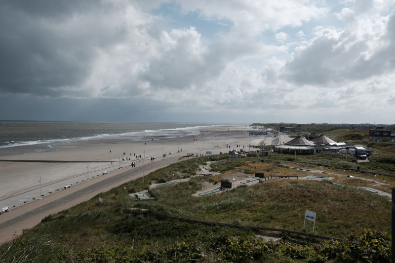 Une vue grand angle de la plage de Norderney avec un ciel nuageux et un rivage en Allemagne.