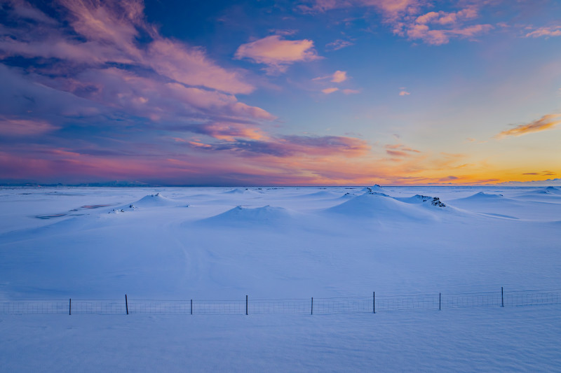 Snowy landscape with colorful clouds at sunset