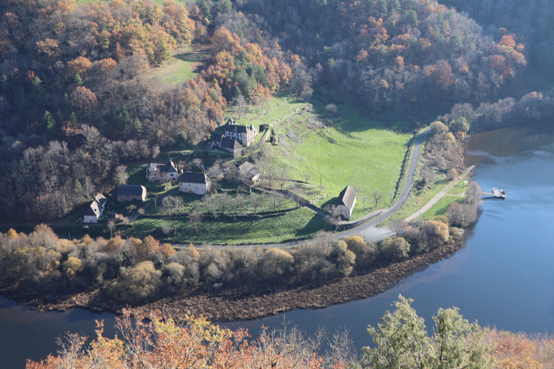 Vue aérienne pittoresque d'une ferme isolée au milieu du feuillage d'automne et d'une rivière en Corrèze, France.